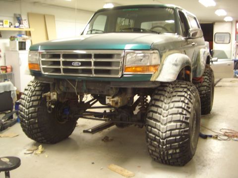 1996 Ford Bronco - This modified Ford Bronco is undergoing work in a garage, a significantly raised suspension and oversized tires.