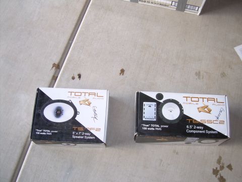 1996 Ford Probe - Two boxes of Total Mobile Audio speakers sit on a concrete surface.