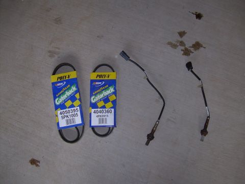 1996 Ford Probe - Two Goodyear Gatorback Poly-V belts and two oxygen sensors are laid out on a concrete surface.