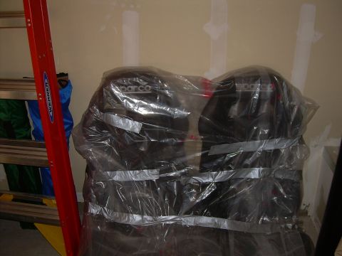 1996 Ford Probe - Two black Sparco car seats are wrapped in plastic and secured with duct tape, with a red ladder to the left.