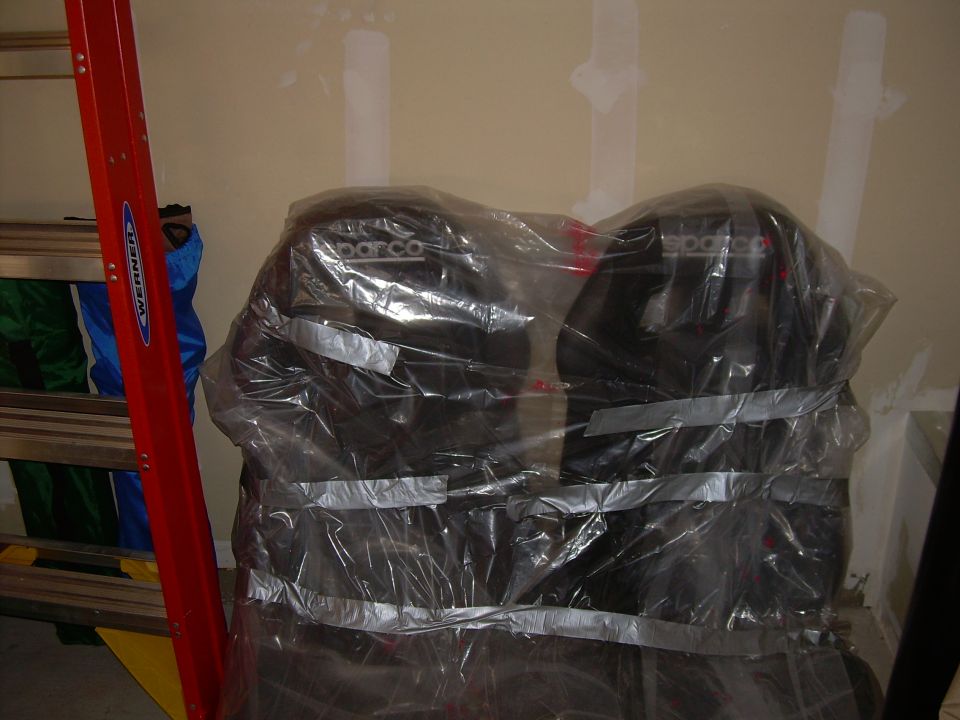 Two black Sparco car seats covered in plastic wrap and duct tape