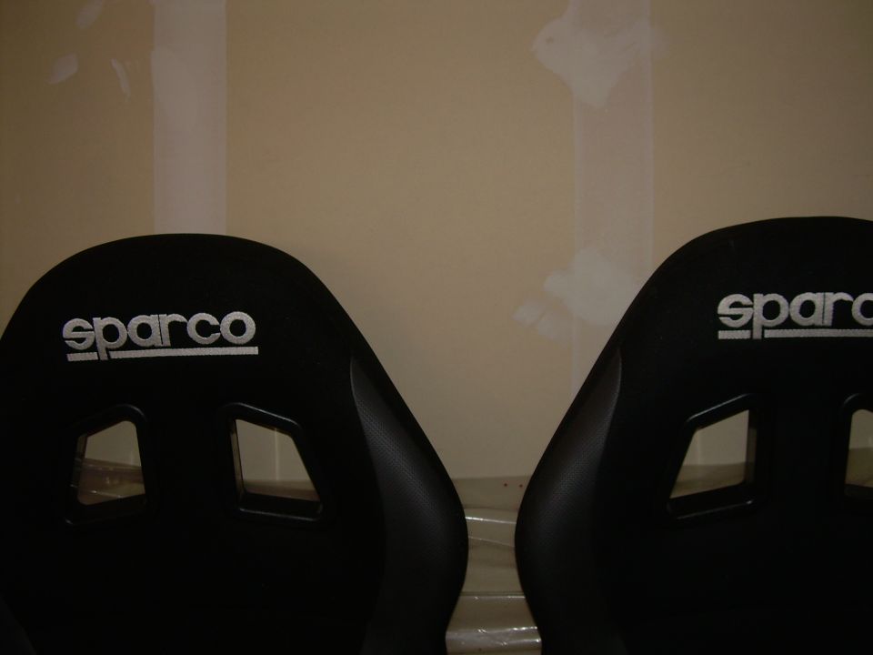Two black Sparco racing seats with white logos, viewed from the front