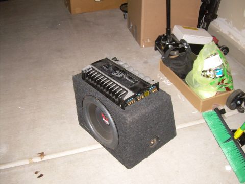 1996 Ford Probe - Car audio amplifier and subwoofer setup, with a car jack and broom nearby.