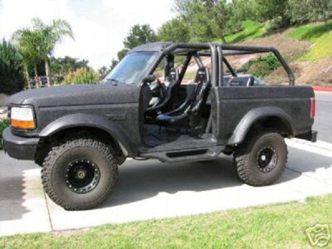 1991 Ford Bronco - This modified Ford Bronco features a roll cage and racing seats, with its doors removed for an open-air experience.
