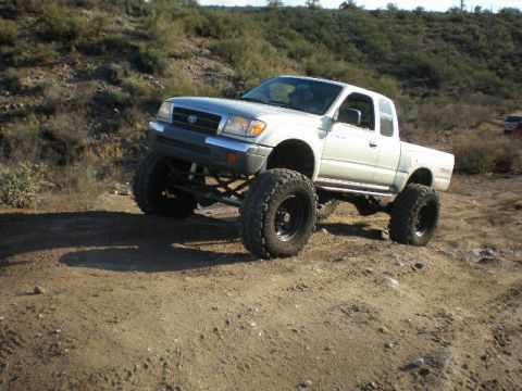 1991 Ford Bronco - A modified Toyota Tacoma is shown off-road with large tires and suspension lift.