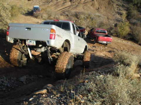 1991 Ford Bronco - Several pickup trucks navigate a challenging off-road course.