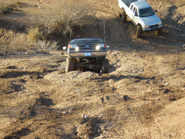 Ford F-Series truck driving on a dirt hill, another pickup truck behind it