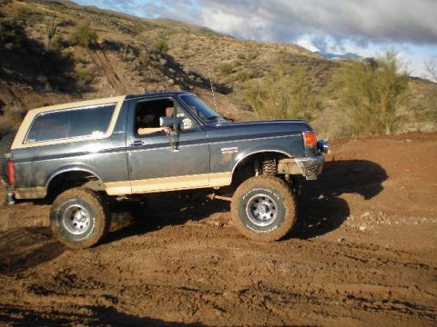 1991 Ford Bronco - This Ford Bronco is shown navigating a dirt trail in a dry, arid landscape.