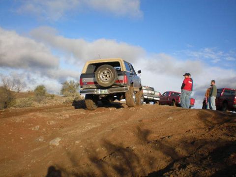 1991 Ford Bronco - A 1991 Ford Bronco navigates a dirt trail with several other vehicles and onlookers present.