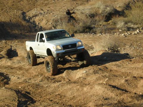 1991 Ford Bronco - This lifted Toyota Tacoma is navigating a rough, dusty off-road course.