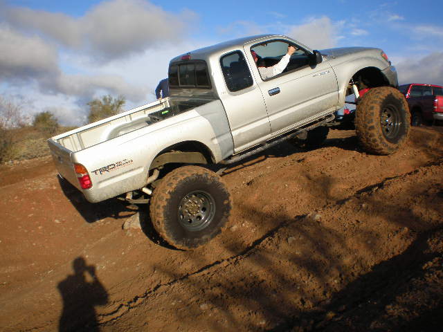 Silver pickup truck with large tires on a dirt hill