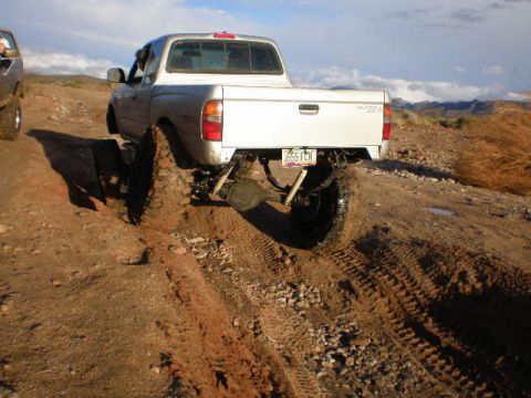 1991 Ford Bronco - Off-road adventure in a lifted Toyota Tacoma, navigating a challenging muddy terrain.