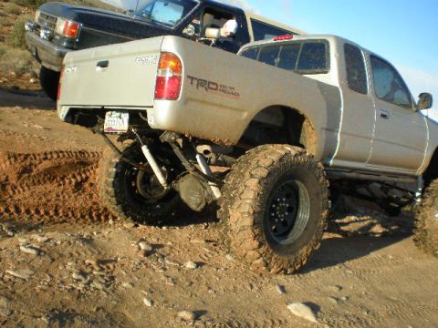 1991 Ford Bronco - A lifted Toyota Tacoma TRD is positioned behind a black SUV on a dusty, off-road trail.