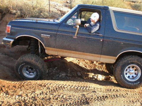 1991 Ford Bronco - A 1991 Ford Bronco navigates a dusty, off-road path.