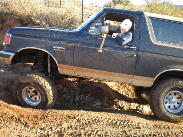 Dark blue 1991 Ford Bronco with lifted suspension navigating an off-road trail