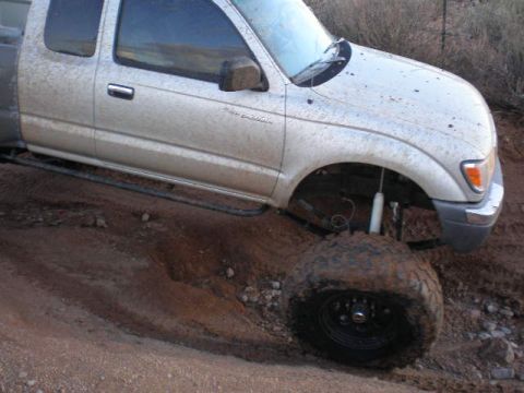 1991 Ford Bronco - This Toyota Tacoma is equipped with large off-road tires and appears to be stuck in muddy terrain.