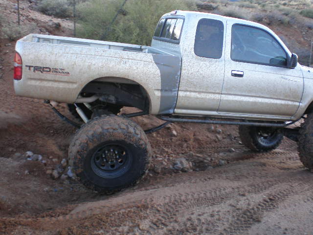 Silver pickup truck with TRD off-road badging and large tires on a dirt trail