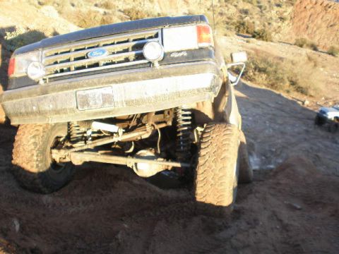1991 Ford Bronco - This Ford Bronco is navigating a steep, dusty incline with another vehicle visible in the distance.