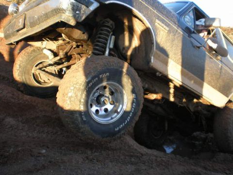 1991 Ford Bronco - This vehicle is covered in mud, with its suspension and tires clearly visible as it navigates rough terrain.