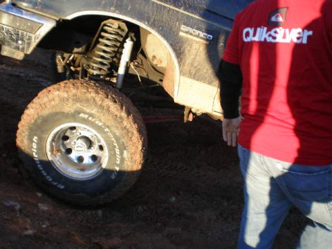 1991 Ford Bronco - A 1991 Ford Bronco is shown from the side, covered in mud, with a person in a Quiksilver shirt standing nearby.