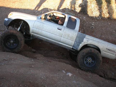 1991 Ford Bronco - Toyota Tacoma TRD off-road vehicle navigating a steep, rocky incline.