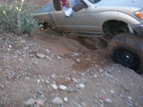 1991 Ford Bronco - A truck is navigating a difficult off-road terrain, getting stuck in a rut.