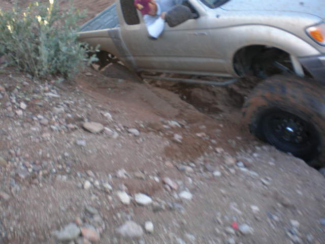 Truck stuck in a ditch on a dirt trail, with one wheel off the ground
