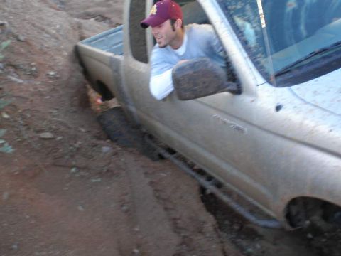 1991 Ford Bronco - A silver pickup truck is stuck in a dirt ditch with a driver looking out the window.