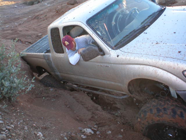 Silver pickup truck stuck in mud, driver looking down