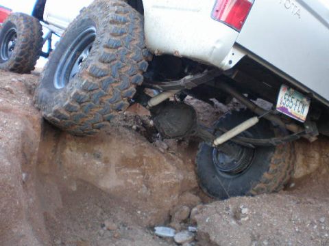1991 Ford Bronco - The rear suspension and large off-road tires of a Toyota truck are visible as it navigates rough terrain.