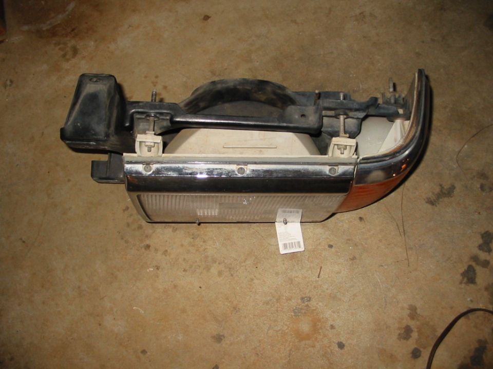 Rectangular sealed-beam headlight assembly with chrome bezel and amber corner lens on concrete