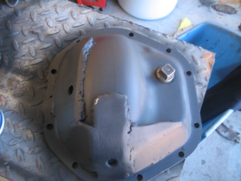 1991 Ford Bronco - A differential cover with weld repairs sits on a diamond plate surface.