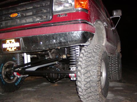 1991 Ford Bronco - Close-up of a lifted 1991 Ford Bronco's front suspension and large off-road tires.