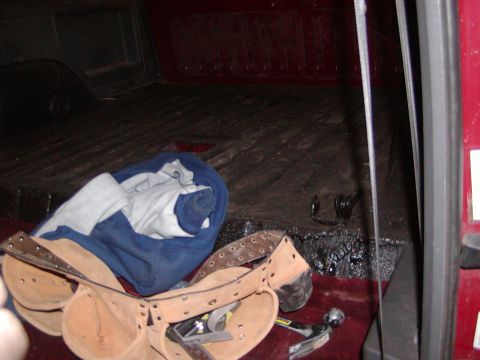 1991 Ford Bronco - Tools and a blanket are stored in the bed of a red vehicle.