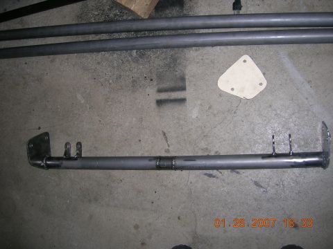 1996 Ford Bronco - A metal tube with welded brackets lies on a concrete surface.