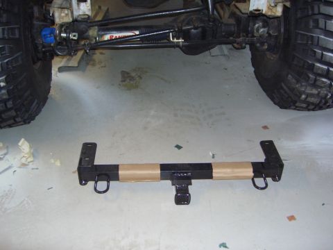 1996 Ford Bronco - A trailer hitch receiver with D-rings is shown, partially wrapped in tan tape, with vehicle suspension and tires visible in the background.