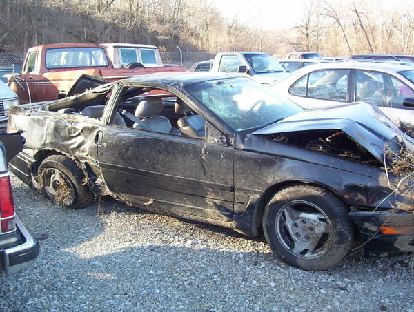 Black 1995 Ford Probe, side view, heavily damaged rear