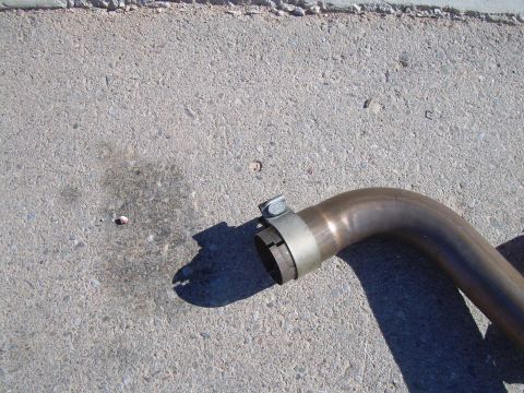 1996 Ford Probe - A clamp secures a section of exhaust pipe resting on a concrete surface.