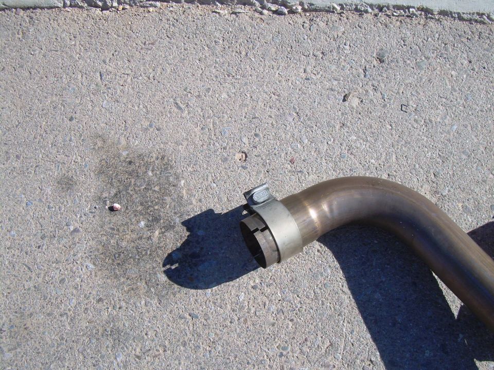 Close-up of an exhaust pipe with a clamp on it, lying on concrete