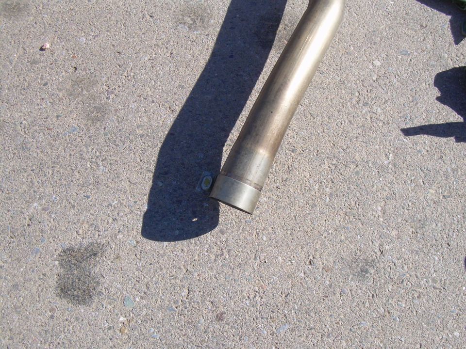 Exhaust pipe section on concrete ground, angled from upper left to lower right