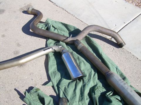 1996 Ford Probe - Several exhaust system components, including pipes and a muffler, are displayed on a green tarp outdoors.