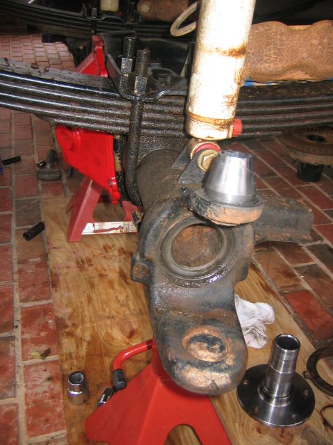 1979 Ford Bronco - Close-up of a vehicle's front axle assembly being worked on, supported by red jack stands.