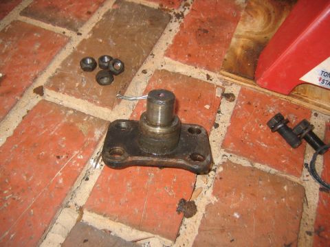 1979 Ford Bronco - A kingpin with its mounting plate and associated nuts are shown on a brick surface, likely during a vehicle repair.