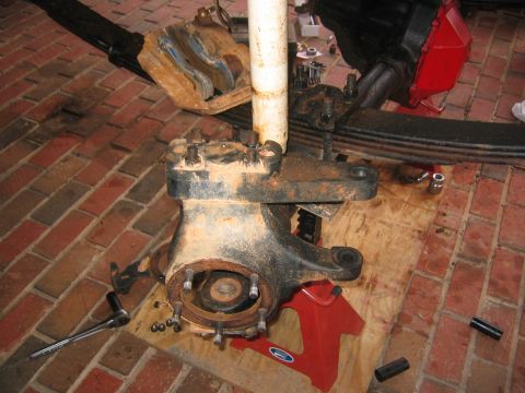 1979 Ford Bronco - Close-up of a vehicle's front axle components, including leaf springs and a shock absorber, during a rebuild.