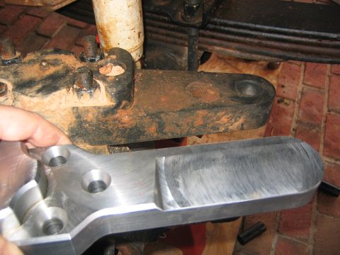1979 Ford Bronco - A new metal part is held near rusty suspension components, suggesting a repair or upgrade.