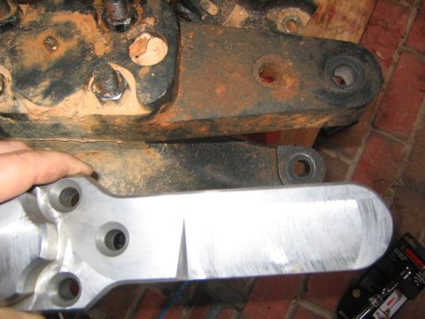 1979 Ford Bronco - A newly fabricated aluminum part is shown next to heavily rusted suspension components, likely for a vehicle repair or upgrade.