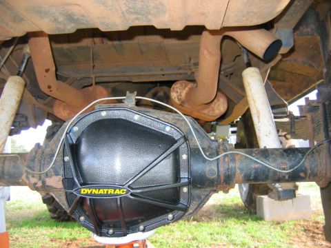 1992 Ford Mustang - The underside of a vehicle reveals a black Dynatrac differential cover and a rusty exhaust system.