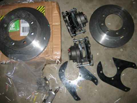 1992 Ford Mustang - Car brake parts including rotors, calipers, and brackets are displayed on the floor.