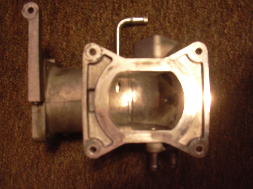 Close-up of a throttle body with a lever arm and a metal tube
