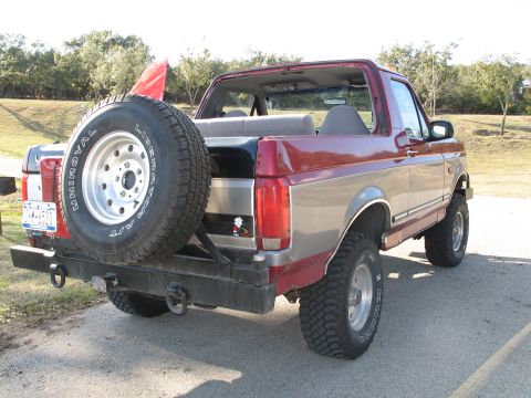 1995 Ford Bronco - A two-door Ford Bronco with a two-tone paint job and a spare tire is parked on a paved surface.